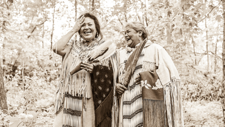Sepia-toned image of two Indigenous women walking in woods
