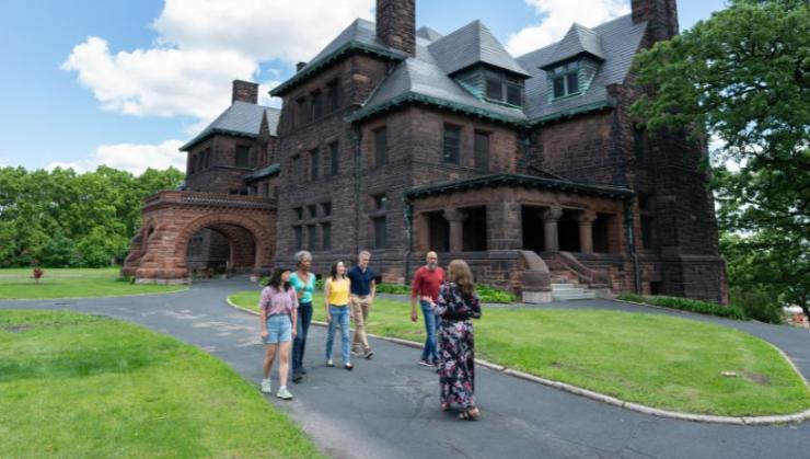 A guide leads a tour group outside Hill House